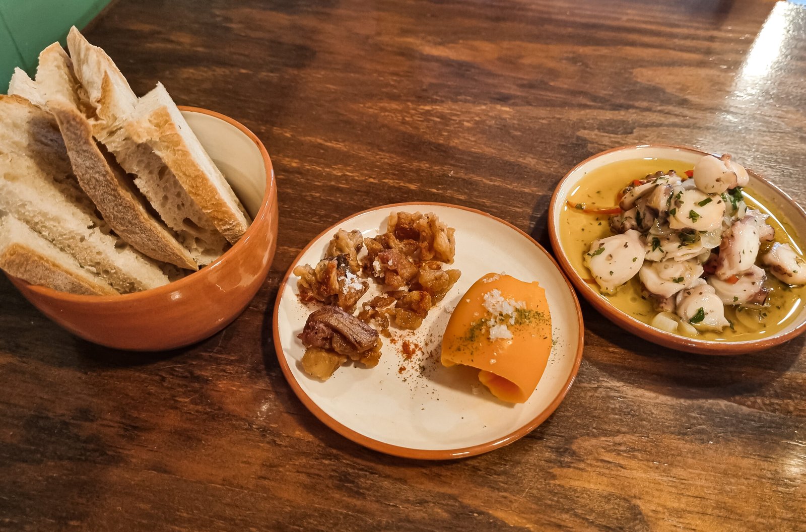 Portuguese small plates — octopus, bread and tapas on a wooden table